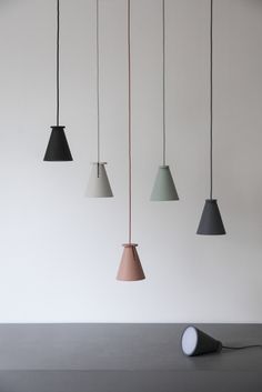 five different colored lamps hanging from the ceiling in a room with white walls and flooring