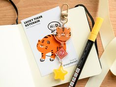 a keychain with a cartoon tiger on it and a pen next to it