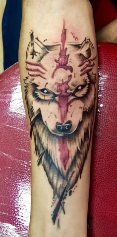 a tattoo with a wolf on it's arm and an arrow in the middle