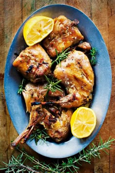 grilled chicken with lemons and rosemary on a blue plate