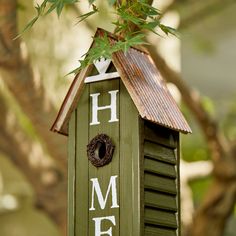 a green birdhouse with the word home painted on it