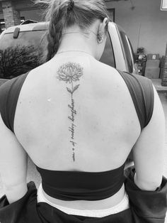 the back of a woman's neck with a flower tattoo on it