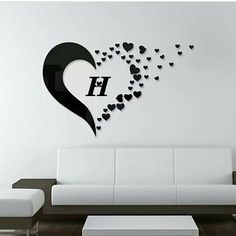 a living room with a white couch and black heart wall decal on the wall