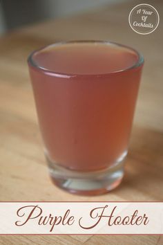 a glass filled with liquid sitting on top of a wooden table