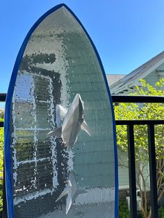 a sculpture of a shark on top of a blue surfboard in front of a house