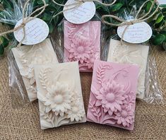 four soaps with flowers on them sitting next to each other in plastic wrappers