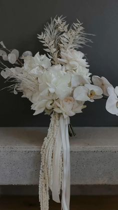 a bouquet of white flowers sitting on top of a table next to a gray wall