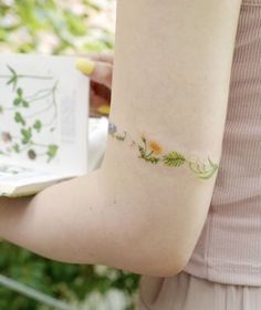 a woman with a small tattoo on her arm holding a book and cup in her hand