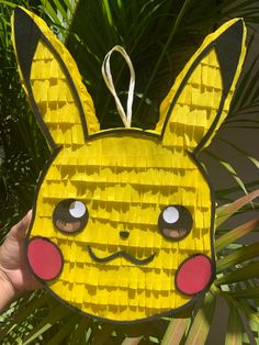 a person holding up a paper cut out of a pokemon pikachu face ornament