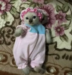 a small stuffed animal laying on top of a bed covered in pink and blue pajamas