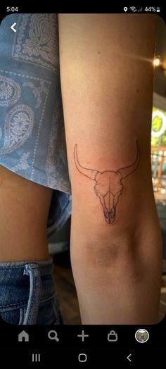 a woman's arm with a small tattoo of a bull skull on the side