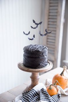 a cake with bats on it sitting on top of a table next to two pumpkins