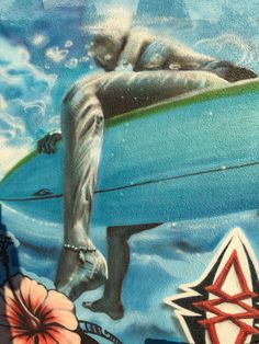 a painting on the side of a building with a person laying on a surfboard