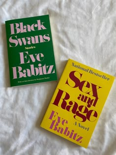 two books sitting on top of a bed next to each other in front of a white sheet