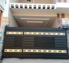 a black and gold gate in front of a white building with brown stripes on it