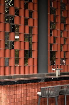 two chairs and a table in front of a building with red bricks on the wall