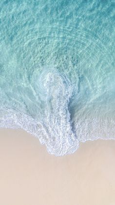 an aerial view of the ocean and beach with waves coming in from the water,