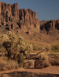 an old suitcase sitting in the desert with mountains in the background