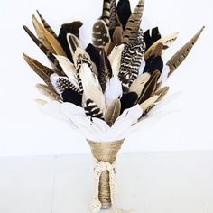 a vase filled with lots of feathers on top of a table