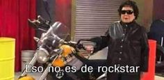 a man standing next to a motorcycle in front of a red curtain with the words eso no es de rockstar on it