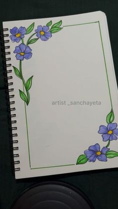 an open notebook with blue flowers painted on the cover and green leaves in the bottom corner