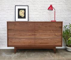 a wooden dresser sitting in front of a white brick wall