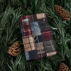 a christmas present wrapped in plaid and tied with twine on top of pine cones