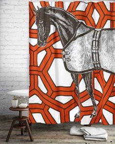 an orange and white shower curtain with a horse on it's side, in front of a brick wall