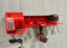 a red work bench mounted to the side of a wall with power tools on it