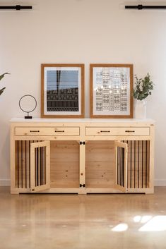 two framed pictures on the wall next to a wooden dog crate with doors and dividers