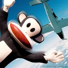 a cartoon monkey flying through the air with an airplane in the background