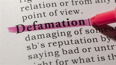 the word defamation is highlighted in a dictionary with a pink marker pointing to it