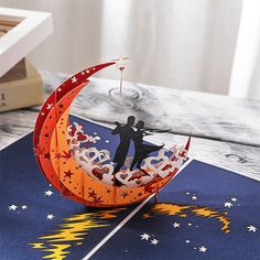 an origami couple kissing on the moon with stars in the night sky as decoration