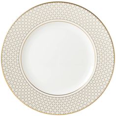 a white and gold plate with an intricate design on the rim, against a white background