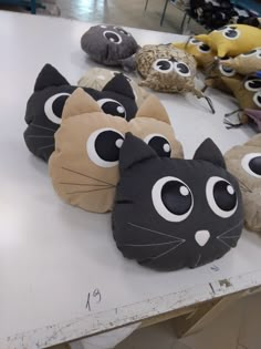 several stuffed animals are on display at a store table with eyes painted on them and one cat's head is in the middle