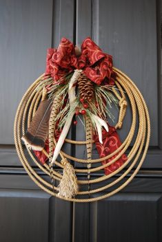 a wreath made out of rope with feathers and other items hanging on the front door