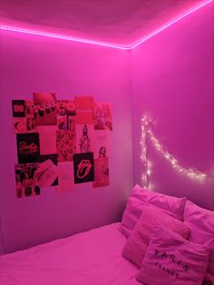 a bedroom with pink lights and pictures on the wall above the bed, along with pillows