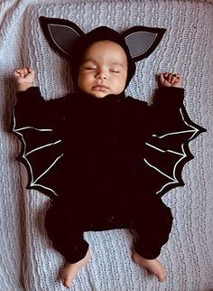 a baby wearing a bat costume laying on top of a bed