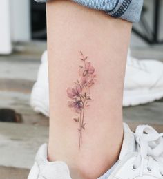 a woman's lower leg with a small flower tattoo on her left side ribcage