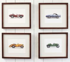 four framed cars are hanging on the wall in front of a white brick wall with brown trim