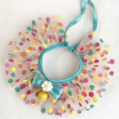 a colorful headband with polka dots and a bell on it's side, attached to a white wall