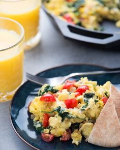 an omelet on a plate with a fork and glass of orange juice in the background