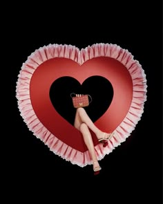 a woman sitting on top of a heart shaped pillow