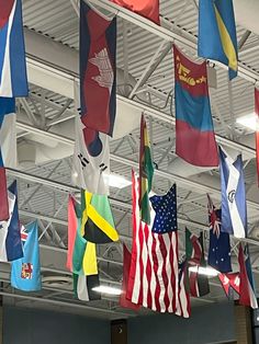 many different flags hanging from the ceiling in a building