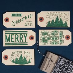 four christmas gift tags on a blue background with twine and paper tag attached to them