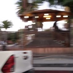 a white truck driving down a street next to a gazebo