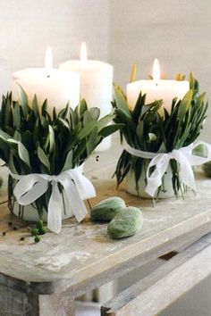 candles wrapped with greenes are sitting on a table