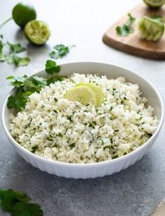 a white bowl filled with rice and garnished with cilantro on the side