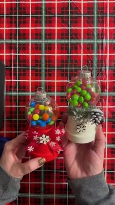 someone is holding up some candy in front of a red plaid wall with snowflakes on it