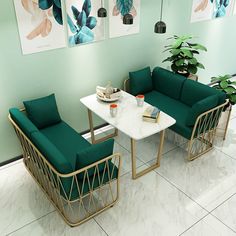 a living room with green couches and white marble top table in front of paintings on the wall